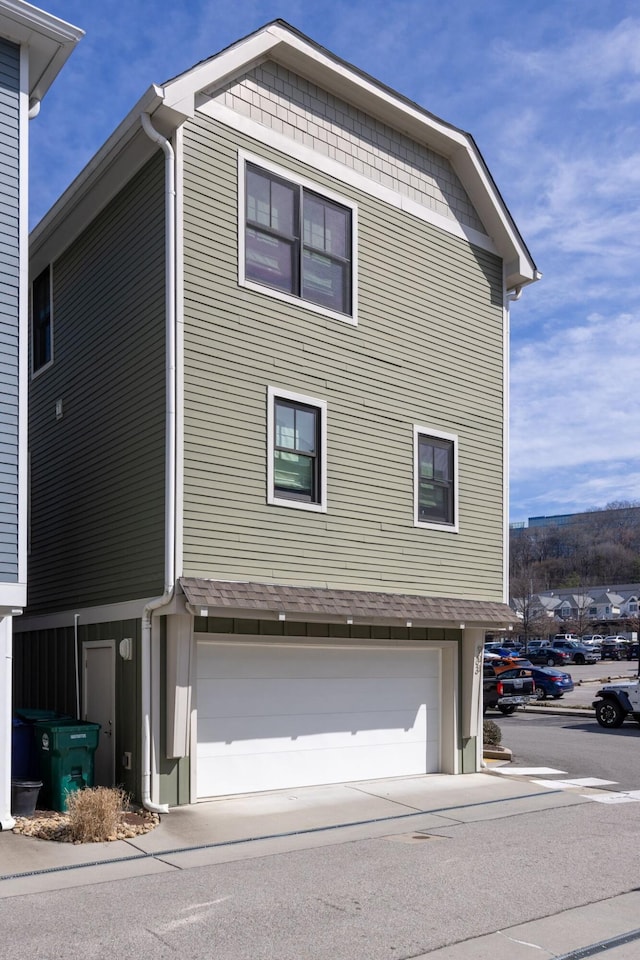 view of side of home featuring concrete driveway and an attached garage