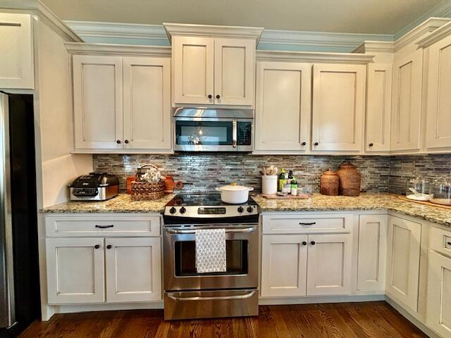 kitchen with dark wood-style floors, decorative backsplash, stainless steel appliances, and light stone counters