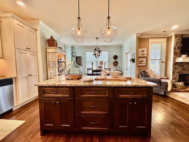 kitchen featuring light stone counters, stainless steel dishwasher, open floor plan, dark wood finished floors, and a stone fireplace