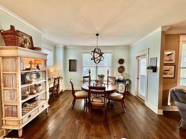 dining area with a notable chandelier, dark wood-type flooring, baseboards, and ornamental molding