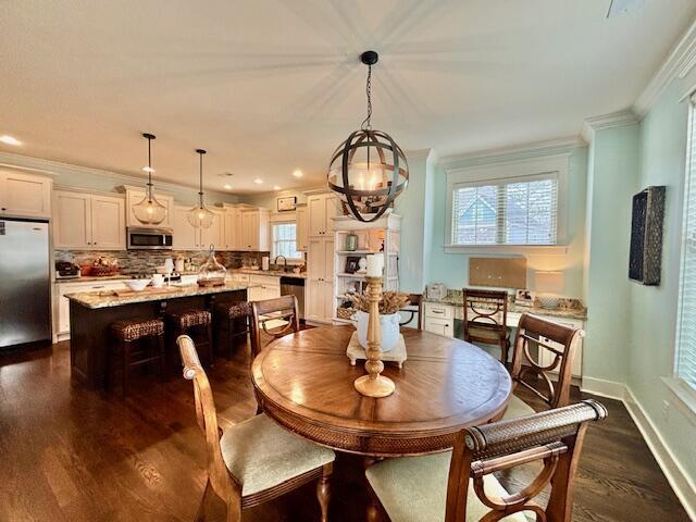 dining space with dark wood-style floors, baseboards, and ornamental molding