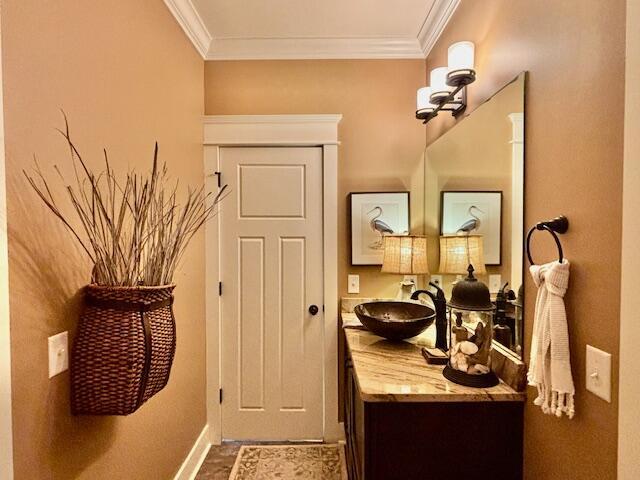 bathroom with vanity, crown molding, and baseboards