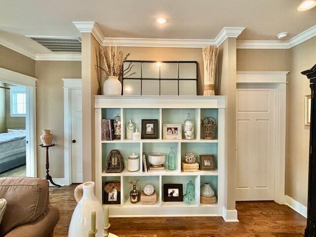 mudroom with baseboards, wood finished floors, visible vents, and ornamental molding