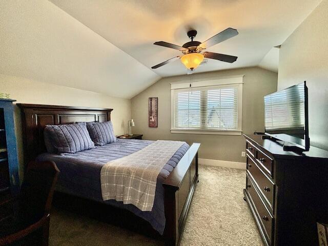 bedroom featuring baseboards, light colored carpet, a ceiling fan, and vaulted ceiling