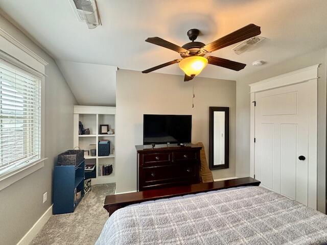 carpeted bedroom featuring lofted ceiling, baseboards, visible vents, and ceiling fan