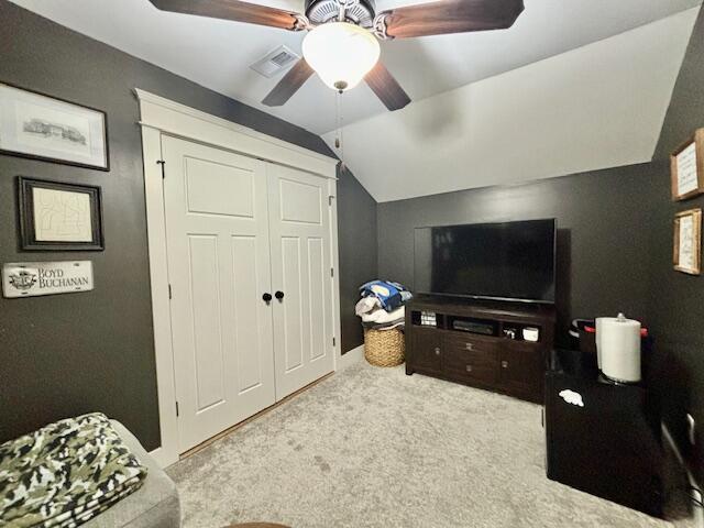 living room featuring a ceiling fan, lofted ceiling, carpet, and visible vents