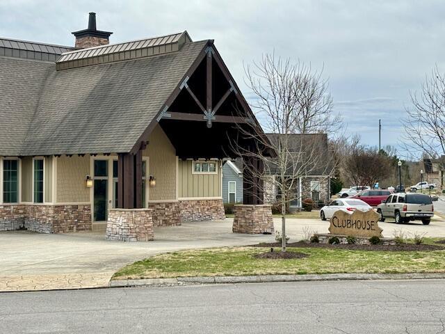 view of front of property with concrete driveway, stone siding, and a chimney