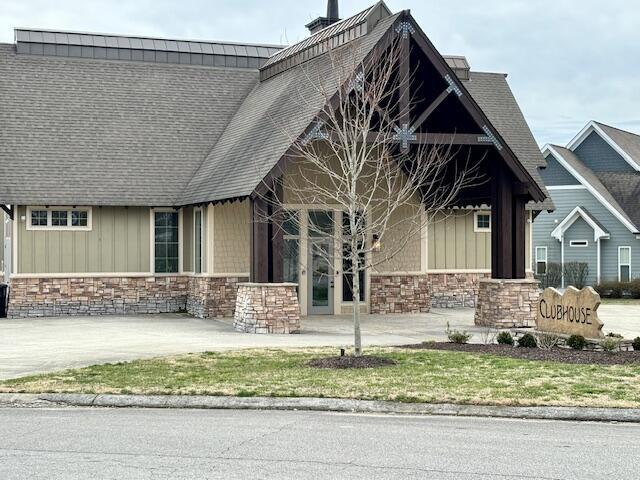 exterior space with stone siding, board and batten siding, and a shingled roof