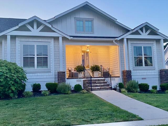 view of front of property featuring a front lawn, covered porch, board and batten siding, a shingled roof, and crawl space