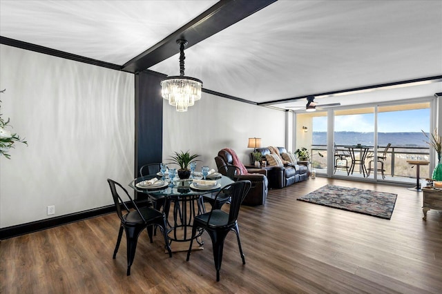 dining room featuring ceiling fan with notable chandelier, a mountain view, wood finished floors, and baseboards