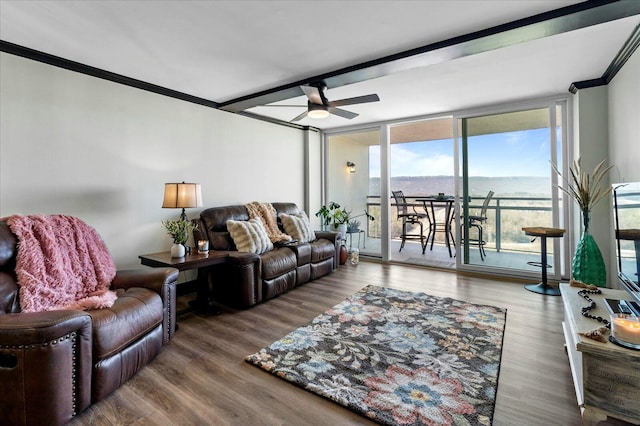 living area with ceiling fan, beamed ceiling, wood finished floors, and ornamental molding