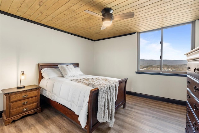 bedroom featuring crown molding, wood ceiling, wood finished floors, and baseboards