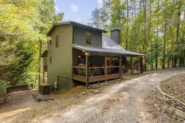 back of property with metal roof, a porch, and a chimney