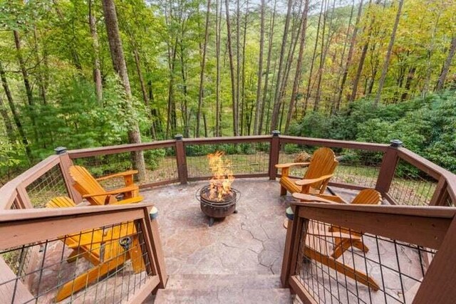 deck featuring a patio, a fire pit, and a wooded view