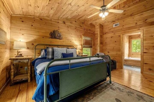 bedroom featuring multiple windows, visible vents, and wood walls