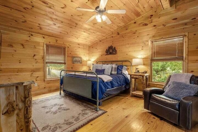 bedroom featuring lofted ceiling, multiple windows, and wood walls