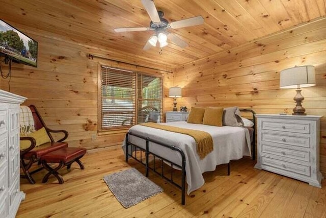 bedroom with ceiling fan, light wood-style flooring, wooden ceiling, and wood walls