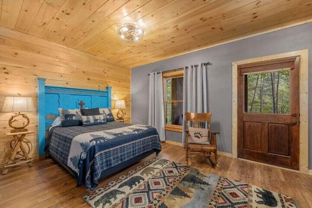 bedroom with wood walls, wooden ceiling, baseboards, and wood finished floors