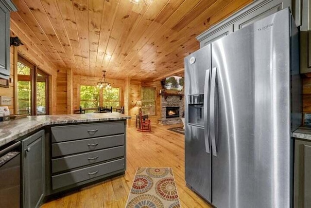 kitchen with light wood finished floors, wooden walls, gray cabinetry, stainless steel fridge with ice dispenser, and dishwasher