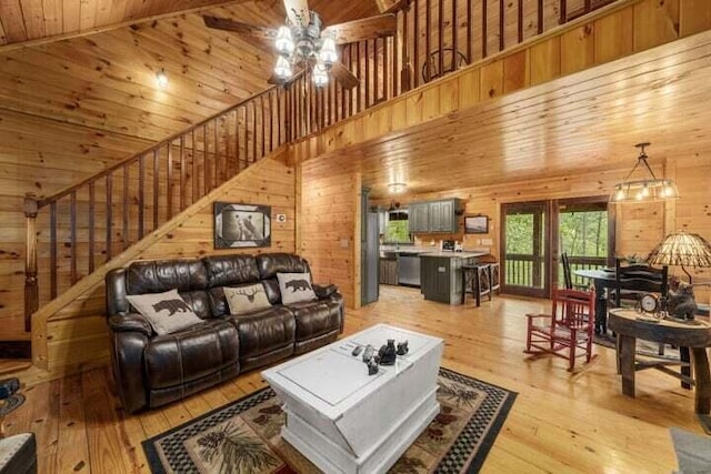 living room with ceiling fan, wood walls, wood ceiling, light wood-style floors, and high vaulted ceiling