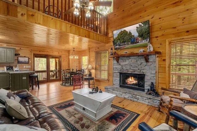 living area featuring a stone fireplace, wood-type flooring, and wood walls