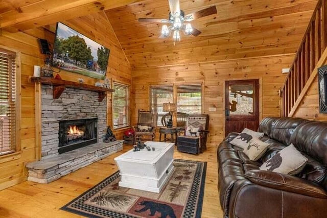 living room with ceiling fan, wood walls, stairs, a fireplace, and wood finished floors