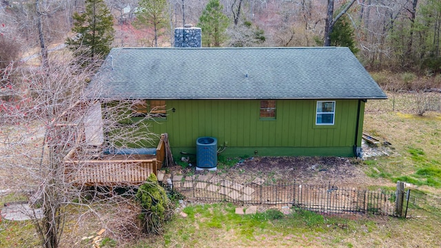 exterior space featuring a shingled roof, a chimney, and fence