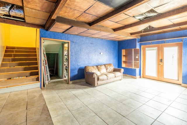 interior space featuring tile patterned flooring, beam ceiling, french doors, and stairs