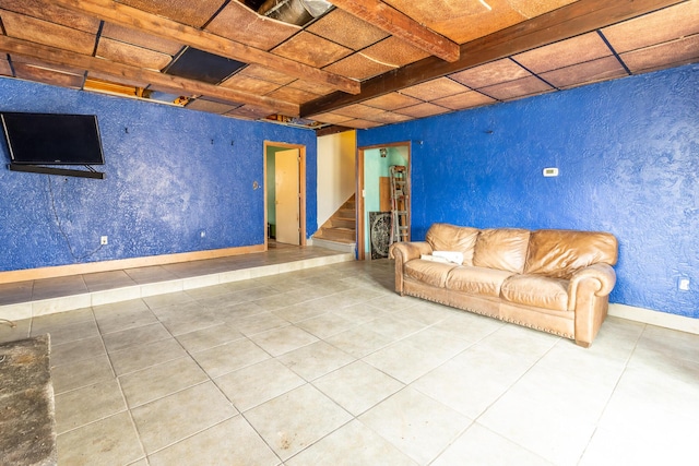 unfurnished living room with tile patterned flooring, stairway, and baseboards