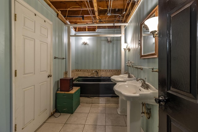 bathroom featuring a garden tub, tile patterned flooring, and a sink