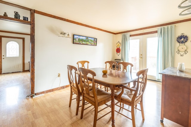 dining room featuring french doors, baseboards, crown molding, and light wood finished floors