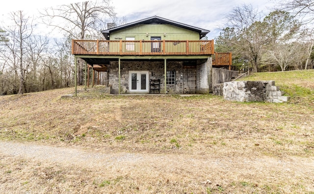 rear view of house featuring stone siding, french doors, and a wooden deck