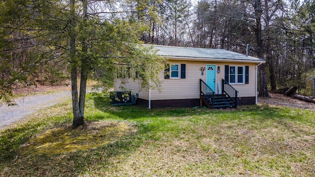 view of front of home featuring entry steps, metal roof, and a front yard