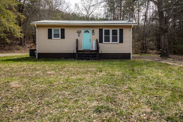 view of front of property featuring entry steps, a front yard, and metal roof