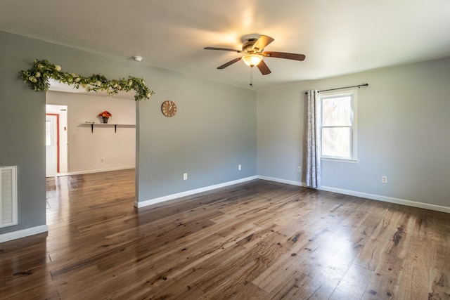 empty room with ceiling fan, visible vents, baseboards, and dark wood-style floors