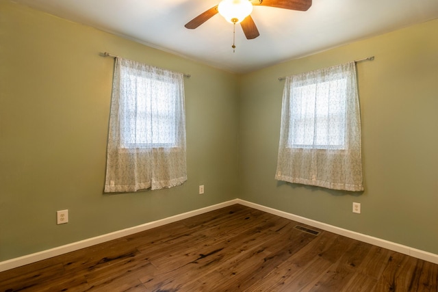 unfurnished room featuring dark wood finished floors, visible vents, a ceiling fan, and baseboards