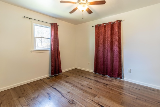 unfurnished room with visible vents, a ceiling fan, baseboards, and wood finished floors