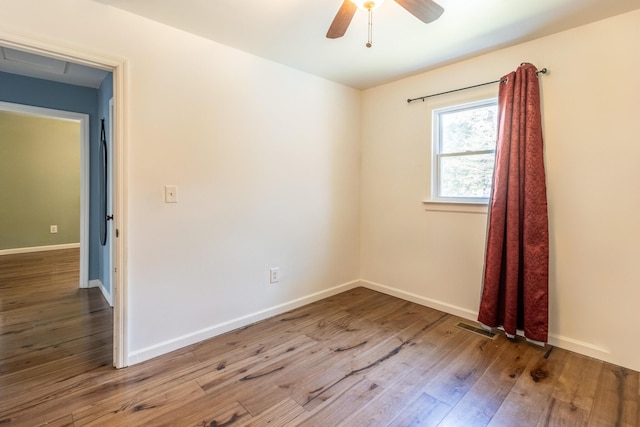 spare room with a ceiling fan, baseboards, visible vents, and wood-type flooring