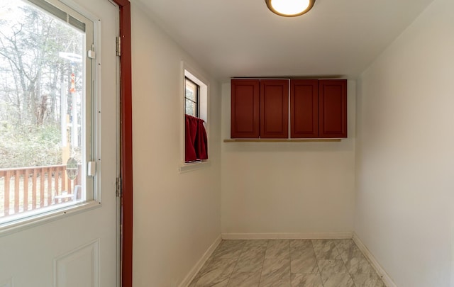 doorway with a wealth of natural light, baseboards, and marble finish floor