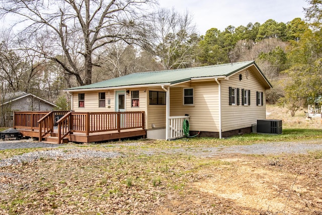 rear view of house with crawl space, cooling unit, metal roof, and a deck