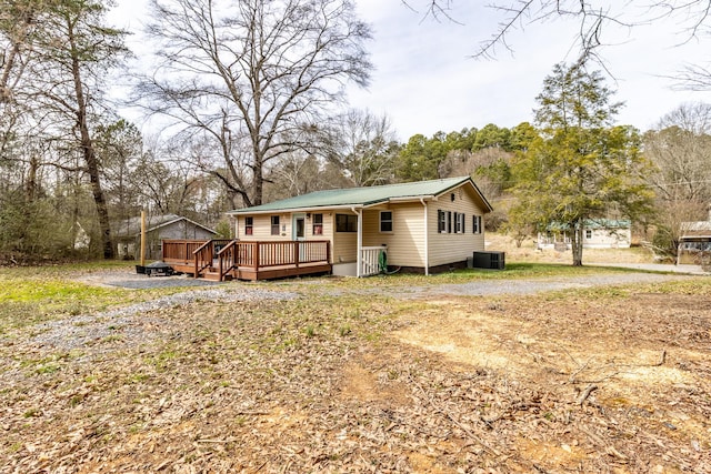 view of front of home featuring a wooden deck, driveway, central AC, and metal roof