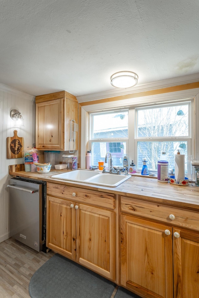 kitchen featuring a sink, stainless steel dishwasher, a textured ceiling, crown molding, and light countertops