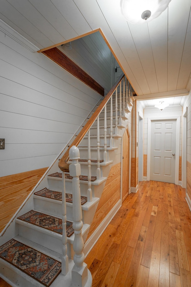 stairs with crown molding and wood-type flooring