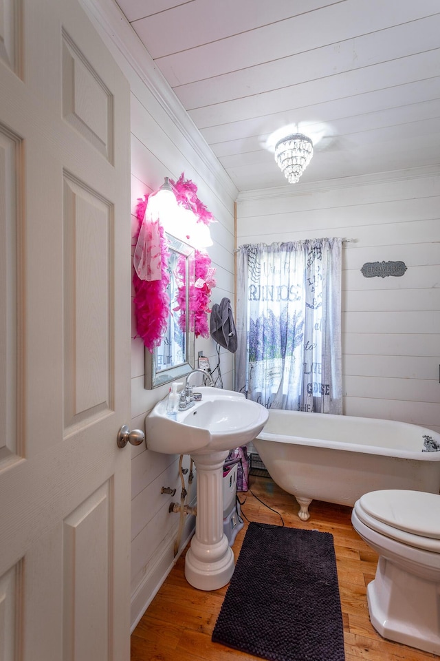 bathroom featuring wood walls, wood ceiling, toilet, a freestanding tub, and wood finished floors