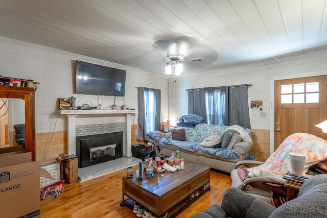 living area featuring a brick fireplace, ceiling fan, ornamental molding, wooden ceiling, and wood finished floors