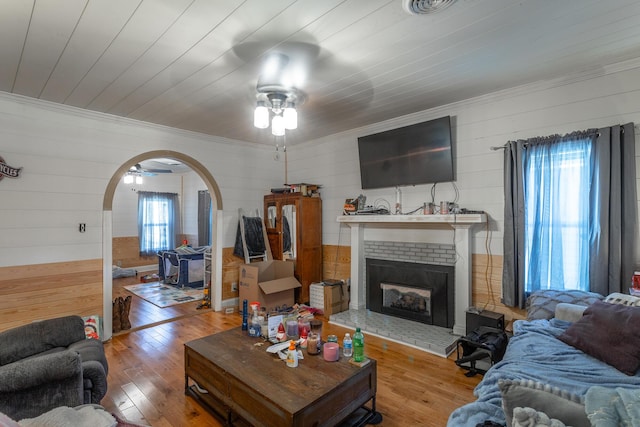 living room featuring plenty of natural light, arched walkways, wood-type flooring, and a ceiling fan