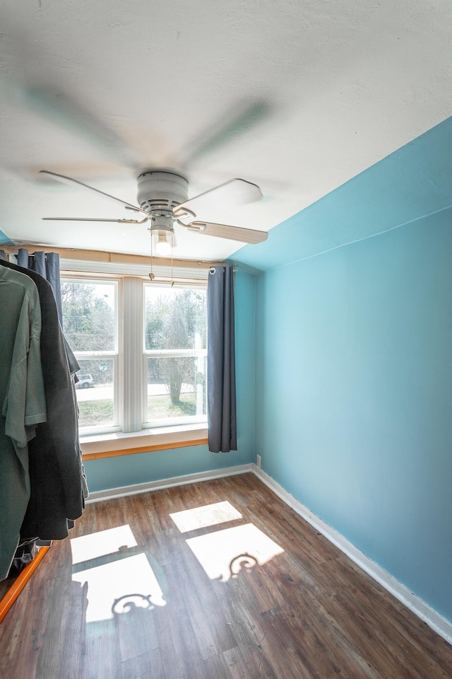 unfurnished room with baseboards, wood finished floors, and a ceiling fan