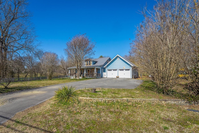 view of front of property with aphalt driveway, a front lawn, an attached garage, and fence