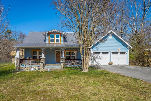 view of front of home featuring driveway, an attached garage, covered porch, a front lawn, and metal roof