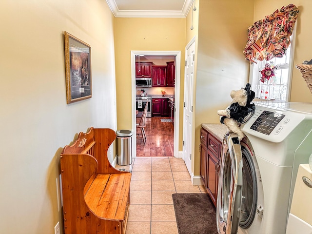 laundry room with baseboards, washing machine and dryer, ornamental molding, light tile patterned floors, and cabinet space